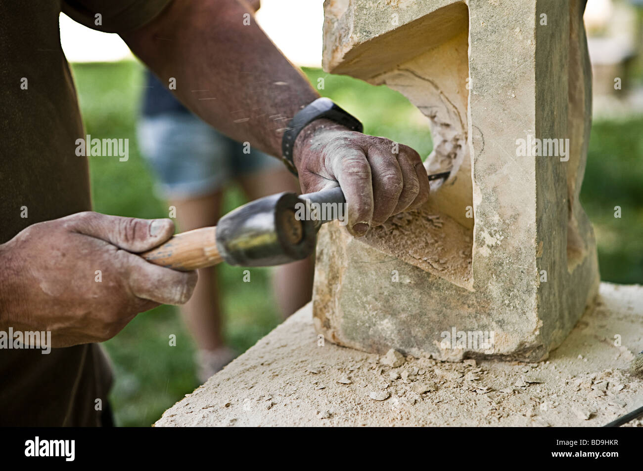 hands of a man sculpting a piece of a white fine grain hard stone Stock Photo
