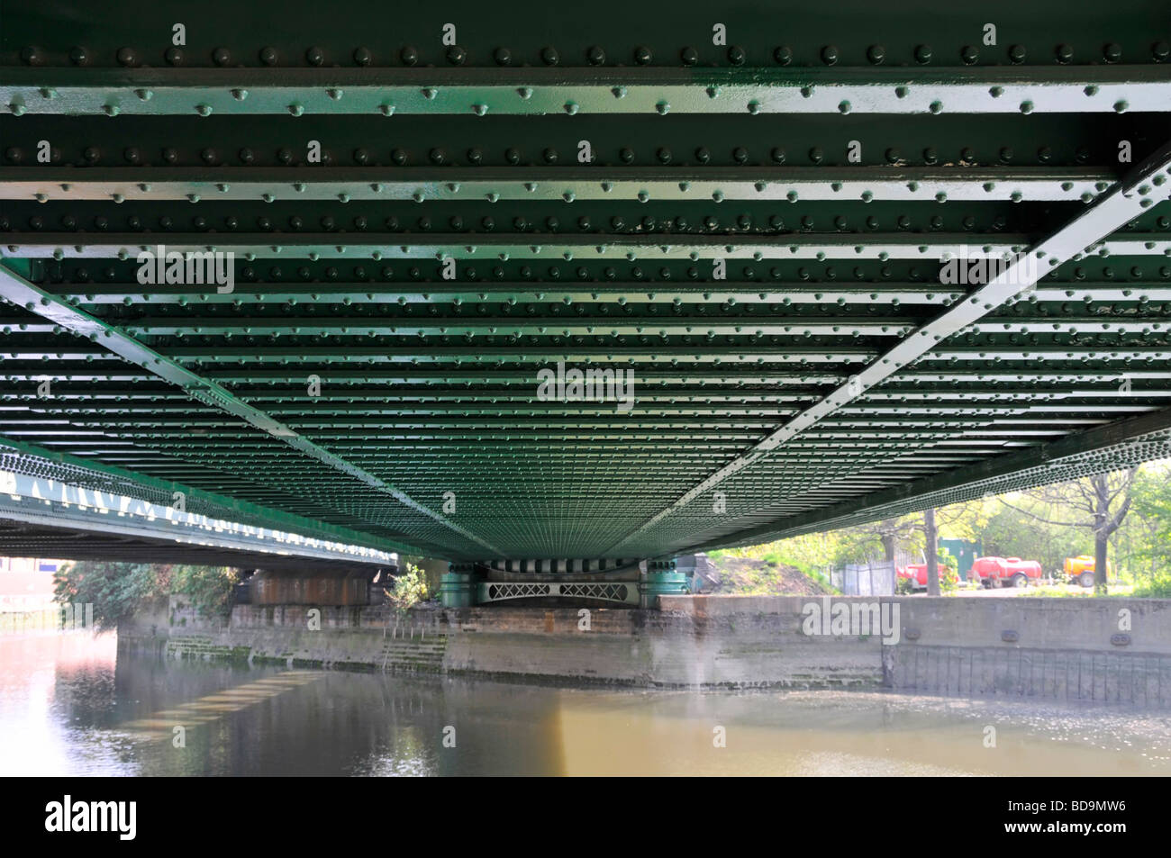 Lines of rivets in steel girders on underside of railway bridge over river Stock Photo