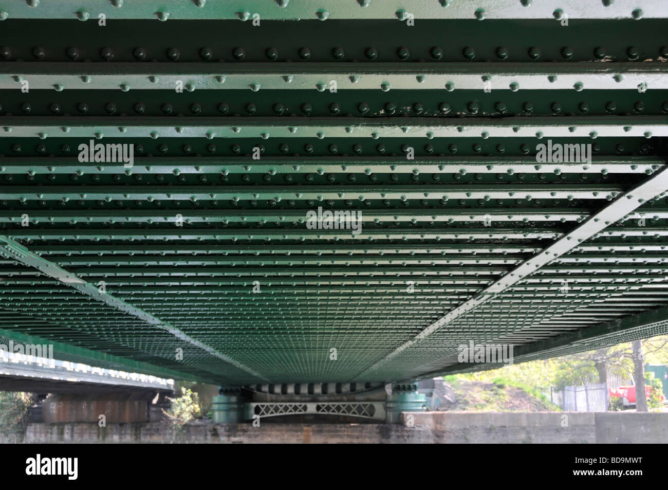 Lines of rivets in steel girders on underside of railway bridge over river Stock Photo