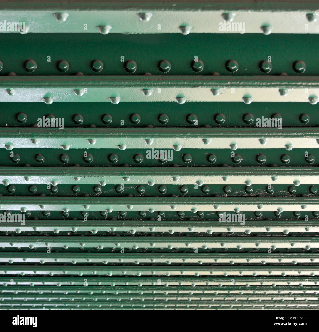 Lines of rivets in steel girders on underside of railway bridge over river close up Stock Photo