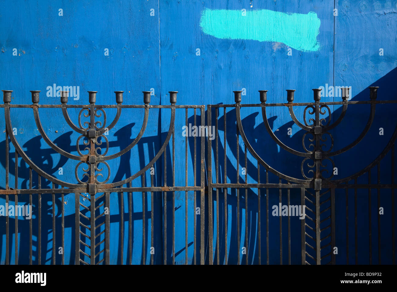 iron gates with the Jewish menorah with dark blue boards in background Stock Photo