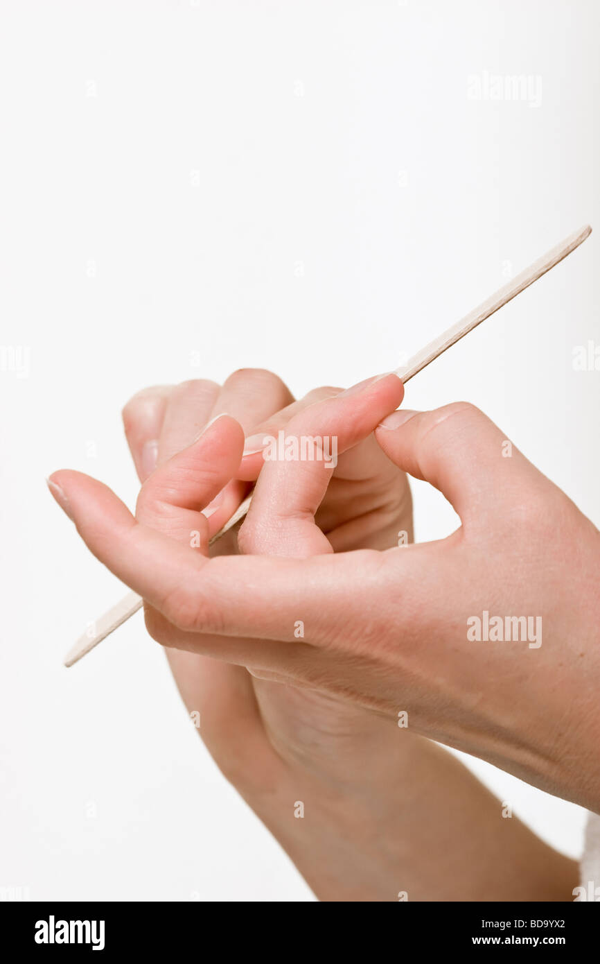 Detail of woman filing her nails against a white background. Stock Photo