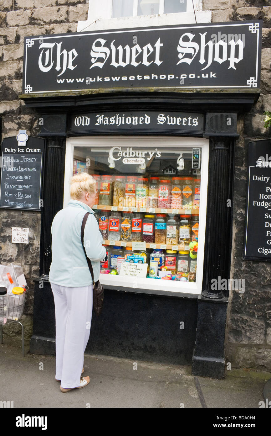 Woman looking at jars of sweets in the window of an old fashioned sweet shop in Kirby Lonsdale Lake District Cumbria England Stock Photo