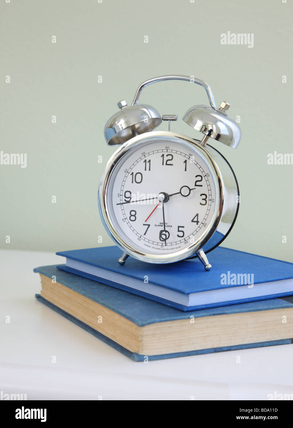 Alarm clock on stack of books Stock Photo