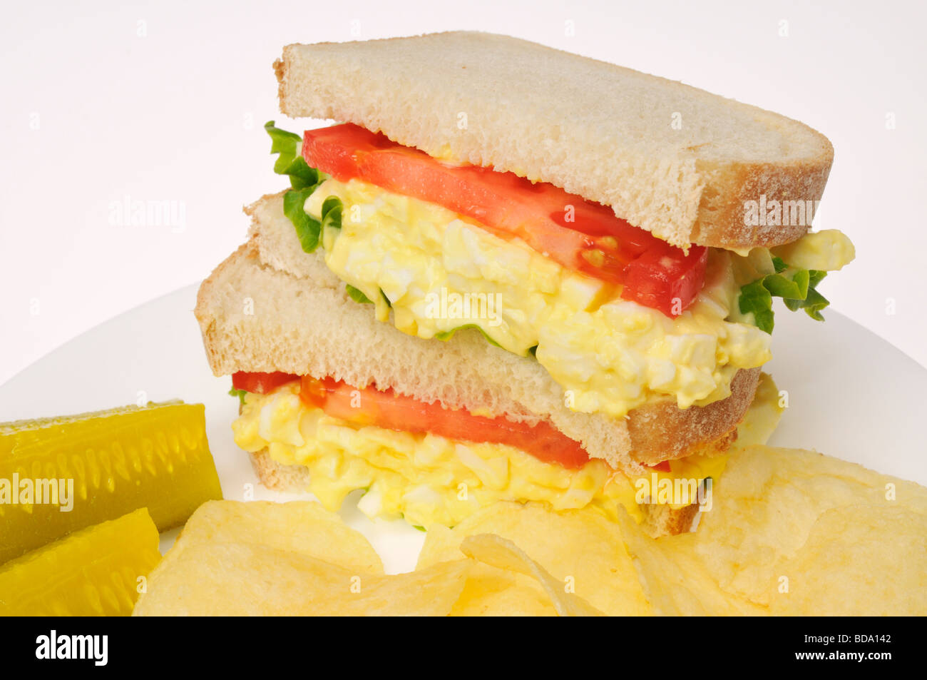 Egg salad sandwich on white bread with lettuce tomato pickles and