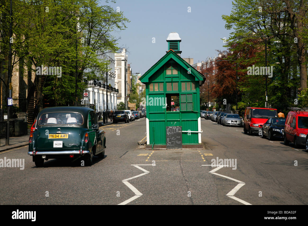 Black cab drives past Cabbies shelter on Kensington Park Road, Notting Hill, London, UK Stock Photo