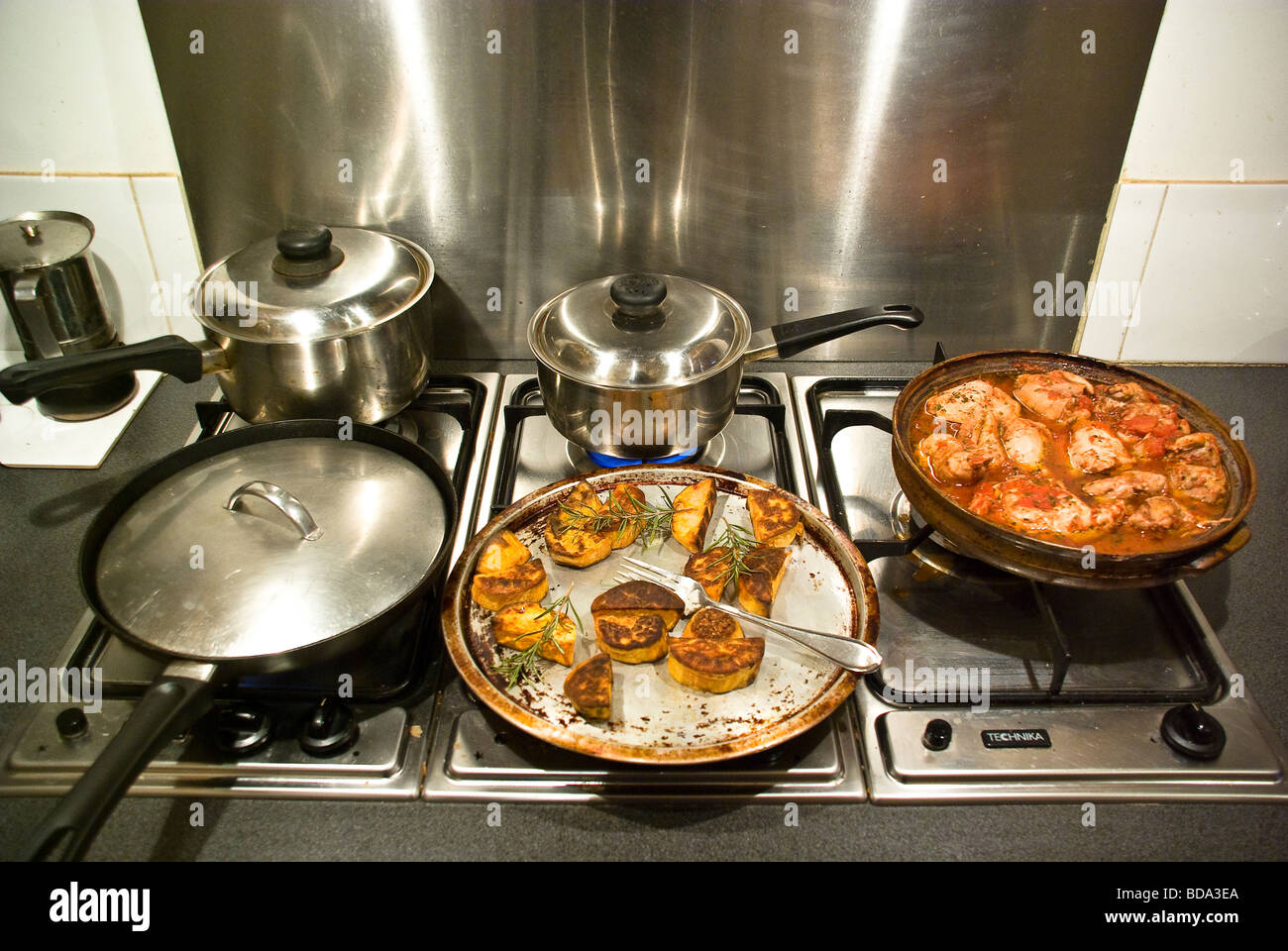 Pots and pans on a gas stove top showing a chicken casserole dish and a