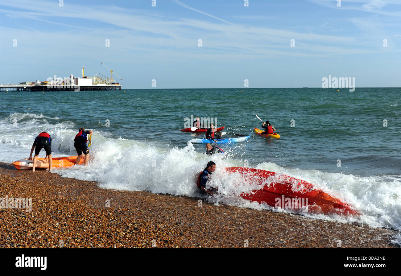 Kayak and canoe club struggle to launch on Brighton beach with waves knocking them over Stock Photo