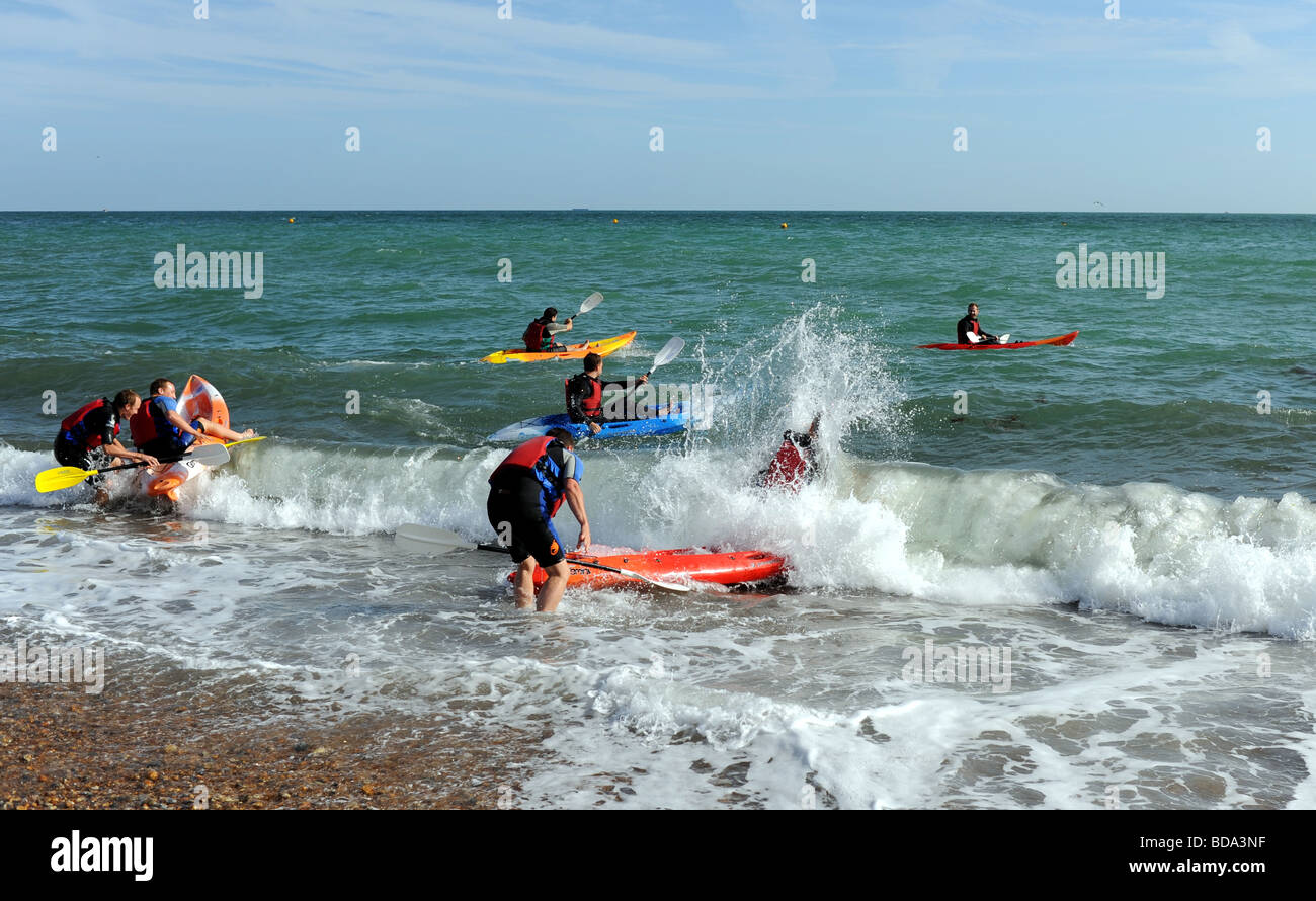 Kayak and canoe club struggle to launch on Brighton beach with waves knocking them over UK summer weather Stock Photo