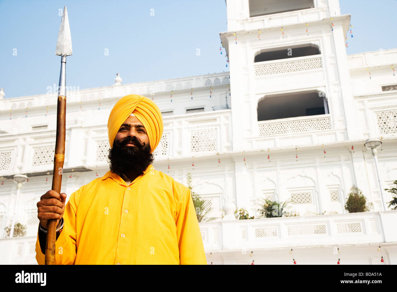 Guard holding a spear in front of a temple, Golden Temple, Amritsar, Punjab, India Stock Photo