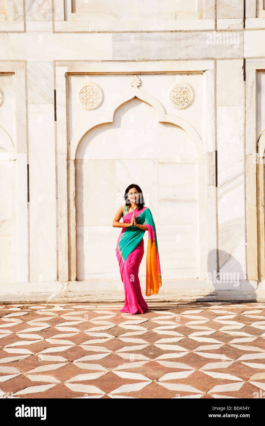 Woman making a greeting gesture in front of a mausoleum, Taj Mahal, Agra, Uttar Pradesh, India Stock Photo