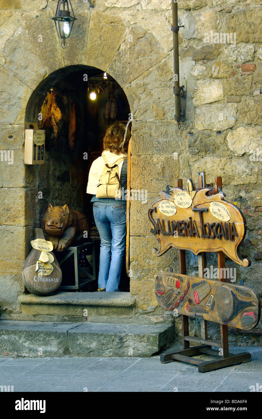 Woman tourist entering a Salumeria Toscana a gourmet food shop just inside the Porta al Prato in Montepulciano Stock Photo