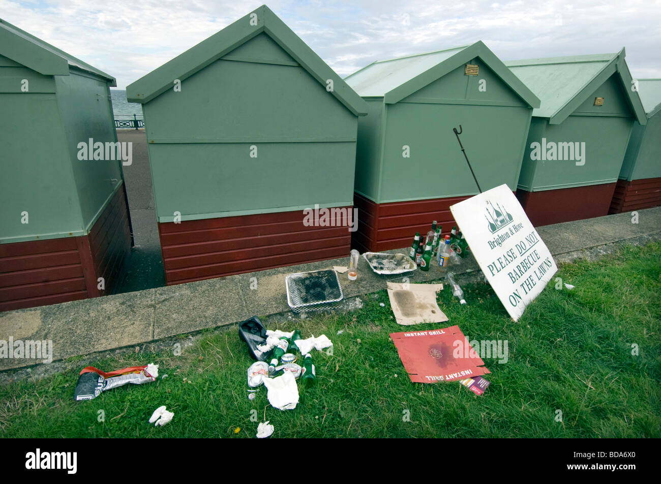 Mess and rubbish by beach huts on Hove lawns, next to a notice asking people not to  barbecue on the lawns. Stock Photo