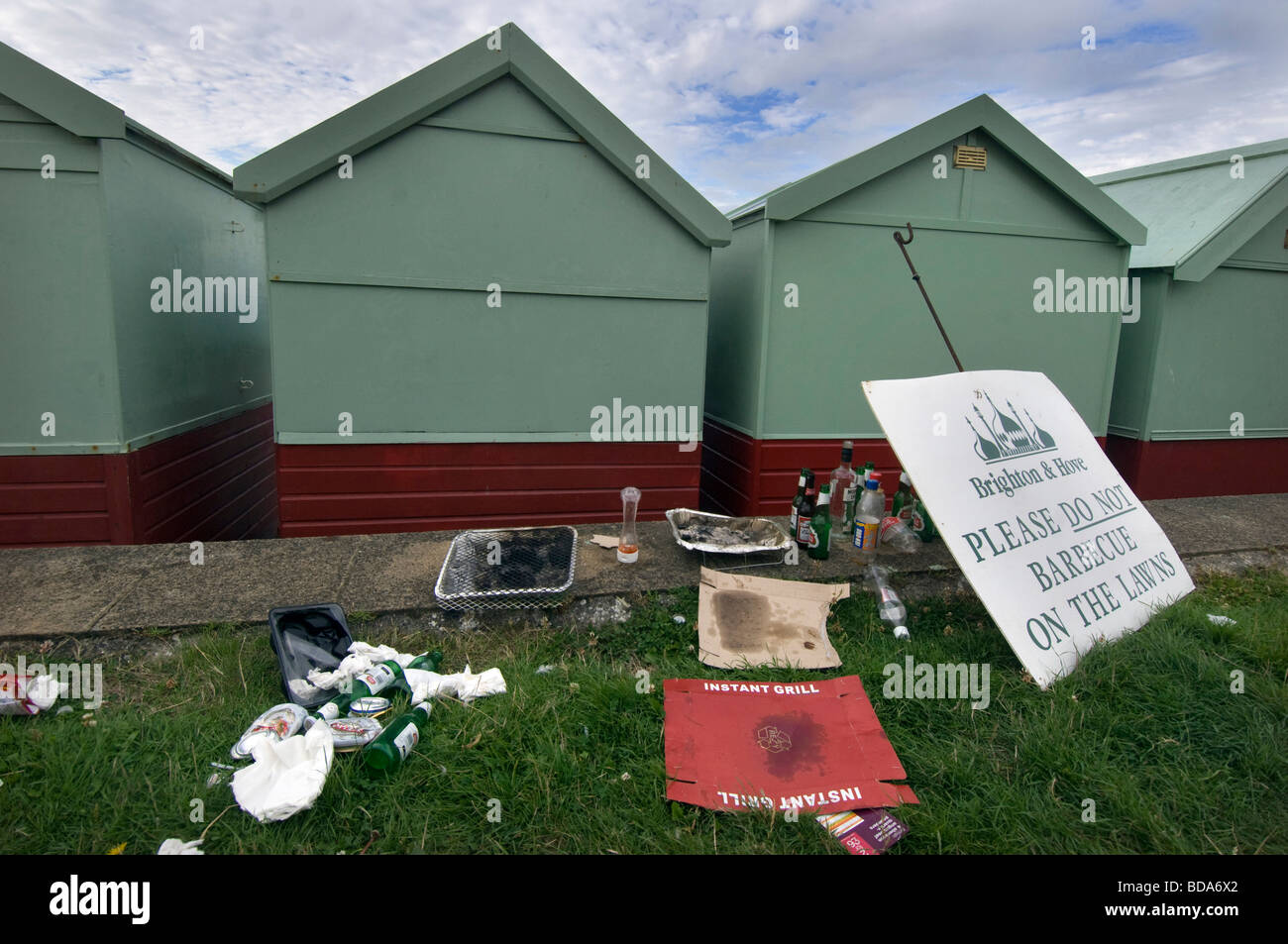 Mess and rubbish by beach huts on Hove lawns, next to a notice asking people not to  barbecue on the lawns. Stock Photo
