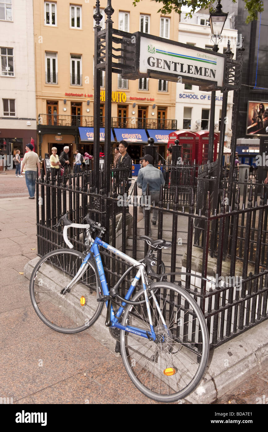 Blue racer push bike secured to the iron railings surrounding the gentlemans  public toilets entrance, Leicester Square, London Stock Photo