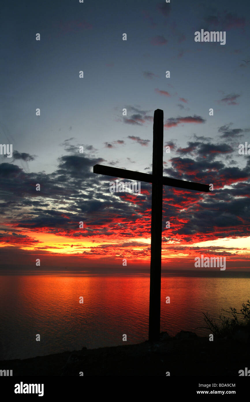 Silhouette of a cross with the sunrising in background Stock Photo