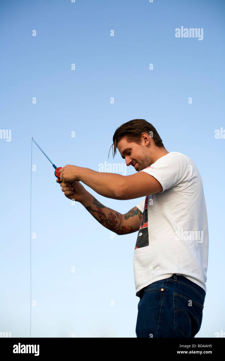 Young man fishing with a small fishing rod Stock Photo - Alamy