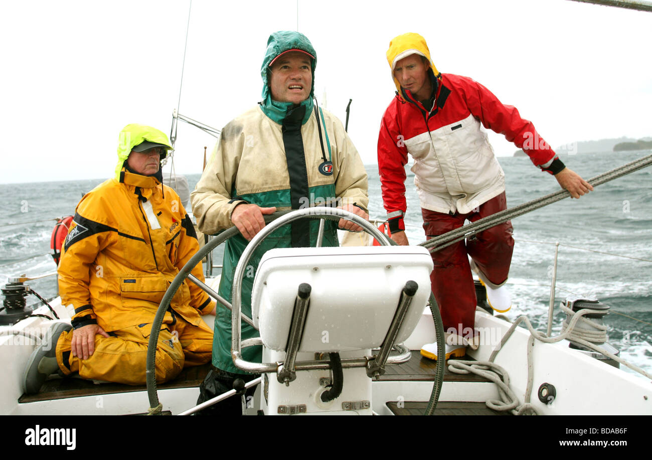 Yachtsmen in wet weather gear on modern yacht Stock Photo
