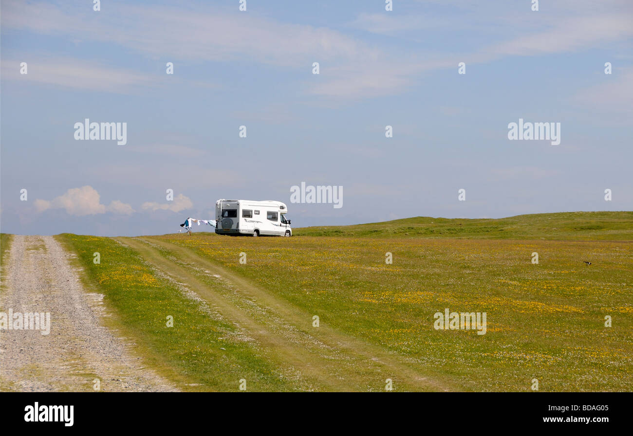 A camper van in an isolated and wild site on the flower covered machair. Washing hangs out to dry in the sun and wind. Stock Photo
