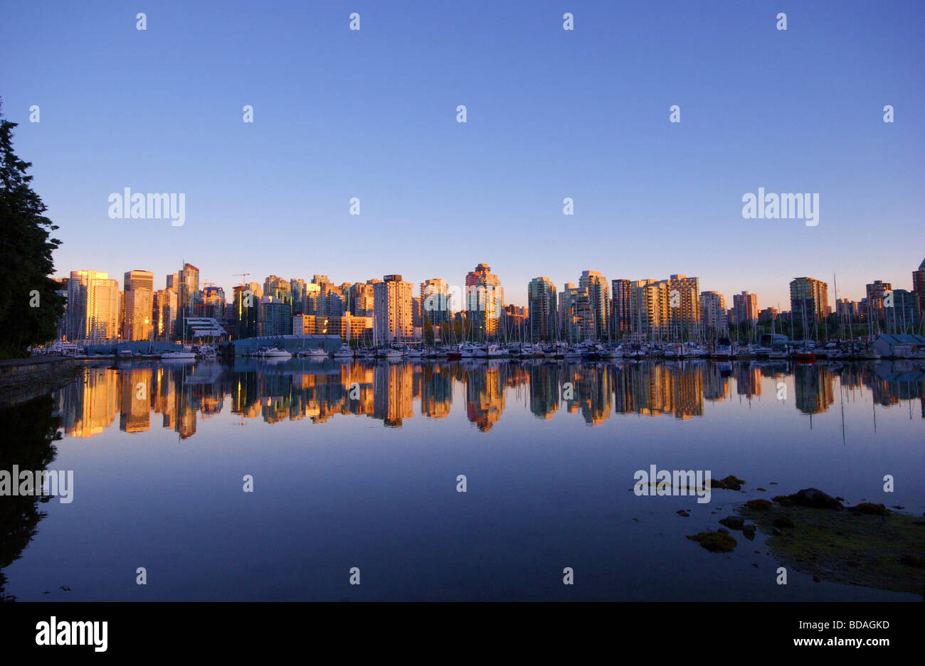 Vancouvers west end condos reflected in the early evening light of Coal Harbour Stock Photo