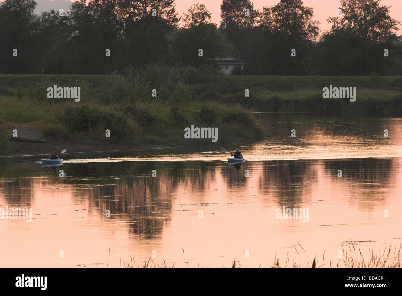 Two kayakers on Alouette River at sunset, Pitt Meadows, BC Stock Photo