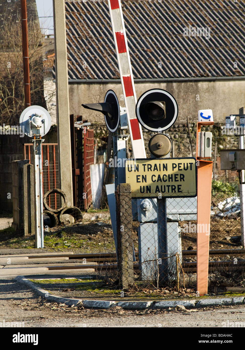 Railroad crossing  with a French warning  sign meaning a train can hid another one Stock Photo