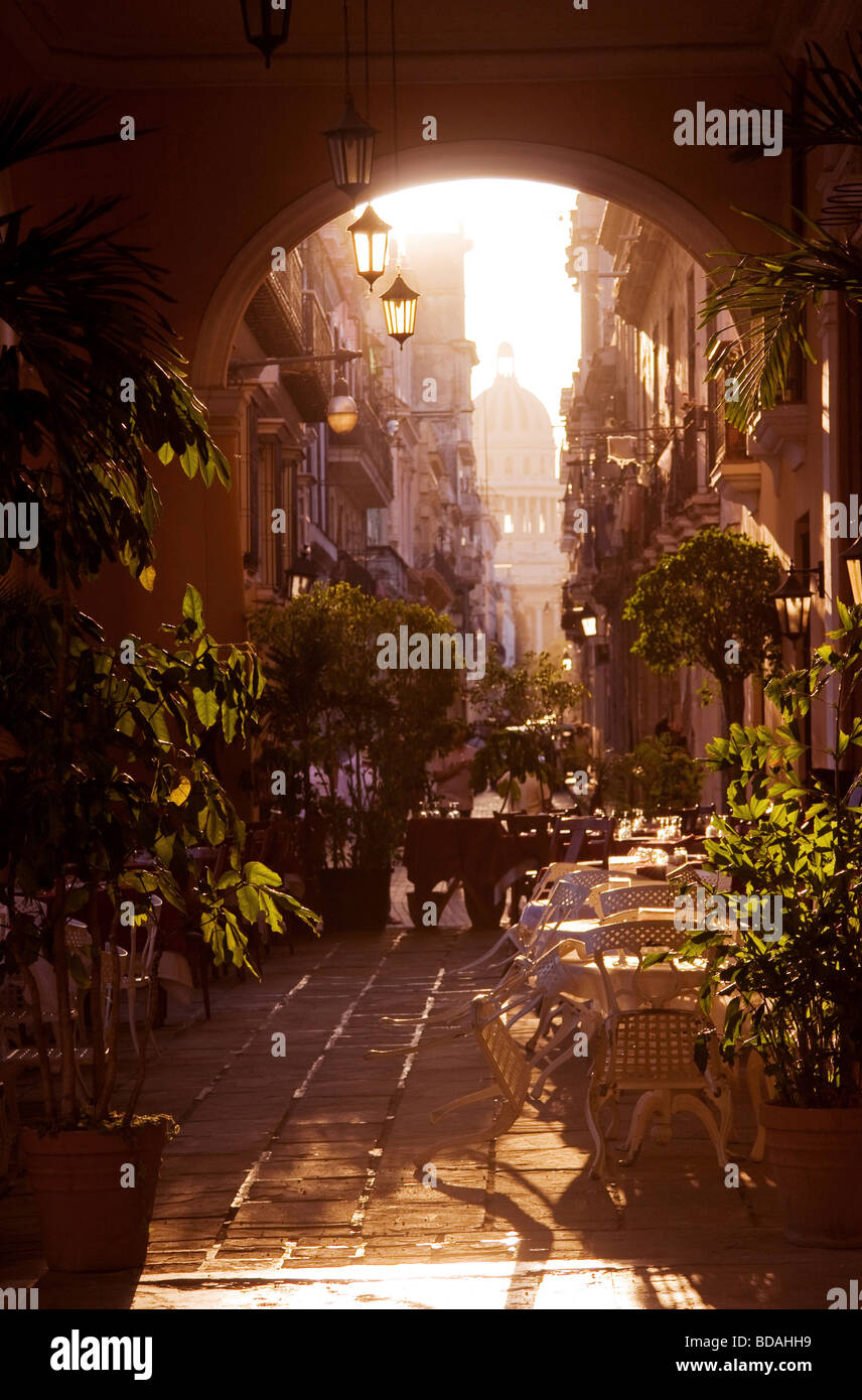 Late afternoon light streams in through archway into outdoor restaurant in Old Havana. Capitolio dome is in the distance. Stock Photo