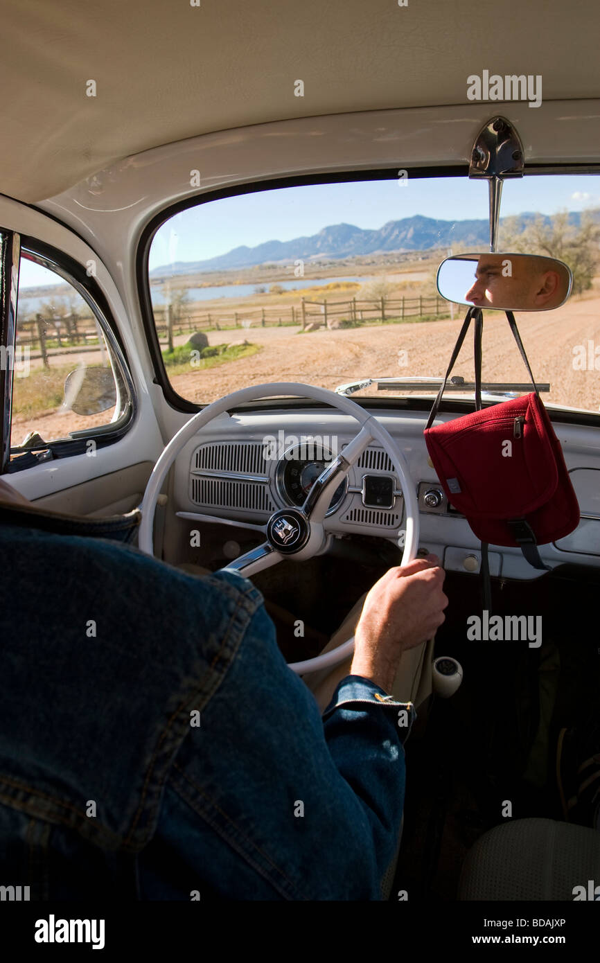 A young couple in a VW bug loaded with luggage drive through the backcountry near Denver, Colorado Stock Photo