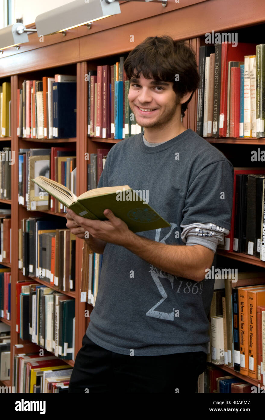 Caucasian young man holding a book and smiling in the library Stock ...