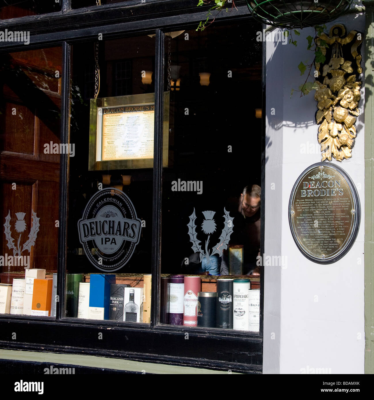 A man seen through a window, browses whisky brands in Deacon Brodies in Edinburgh's Royal Mile. Stock Photo