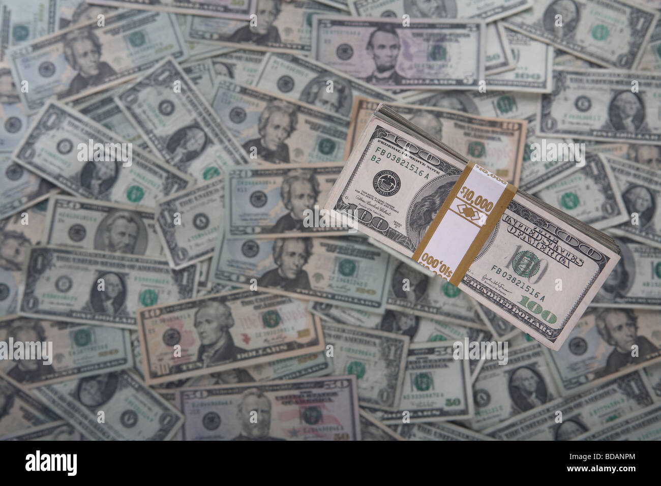A bundled stack of 100 dollar bills on a moderately soft background of US currency Stock Photo