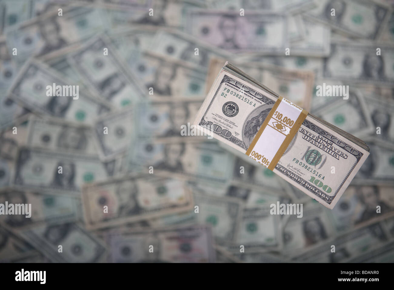 A bundled stack of 100 dollar bills on a very soft background of US currency Stock Photo