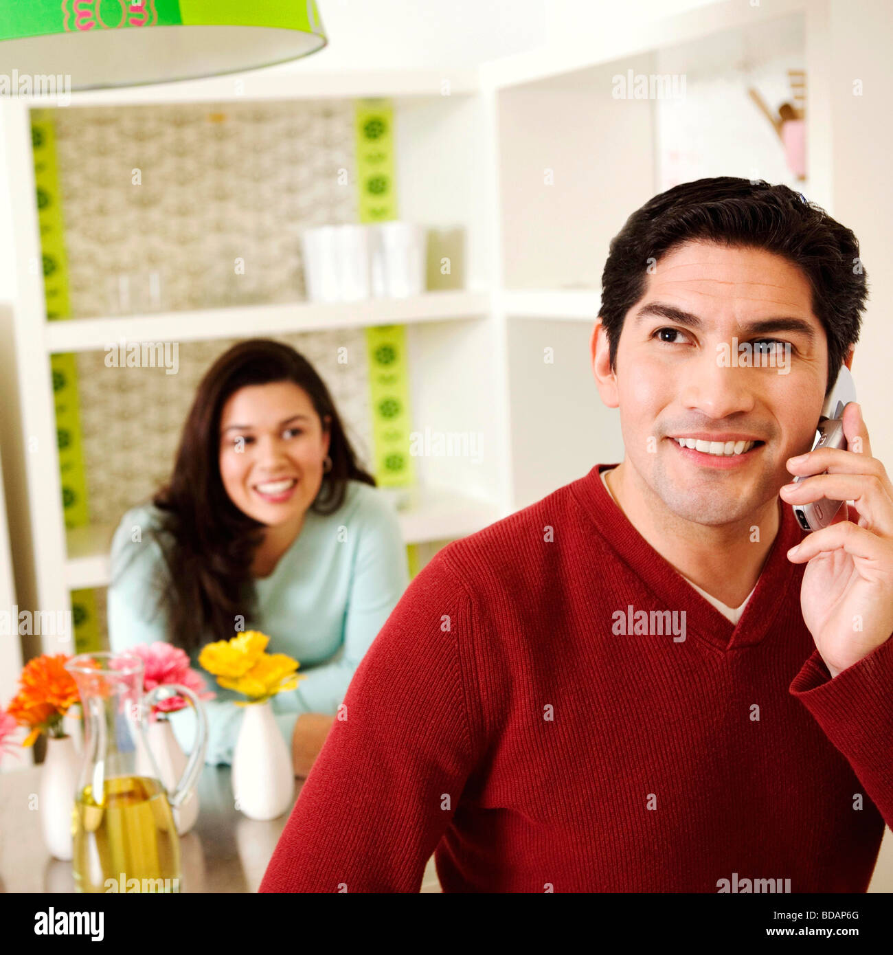 Mid adult man talking on a mobile phone with a mid adult woman smiling in the background Stock Photo