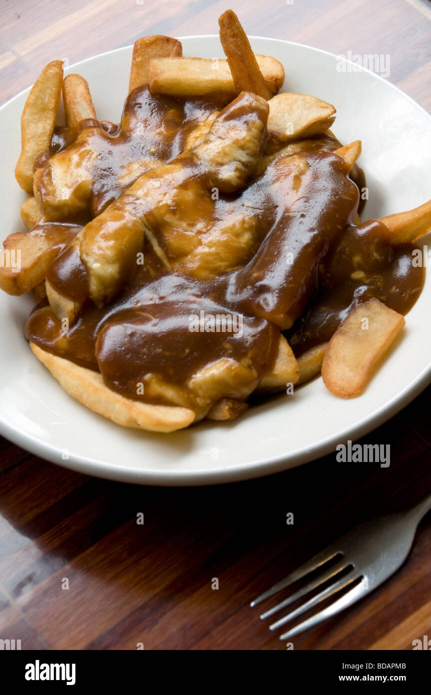 A plate of freshly served poutine - a Canadian delicacy consisting of french fries, gravy and cheese - at a restaurant in Toronto, Canada. Stock Photo