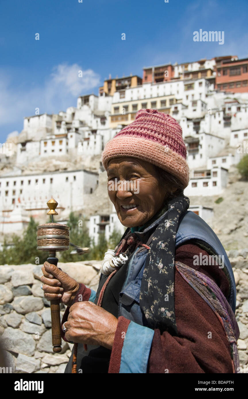 Woman praying with monastery in the background, Thiksey Monastery, Ladakh, Jammu and Kashmir, India Stock Photo