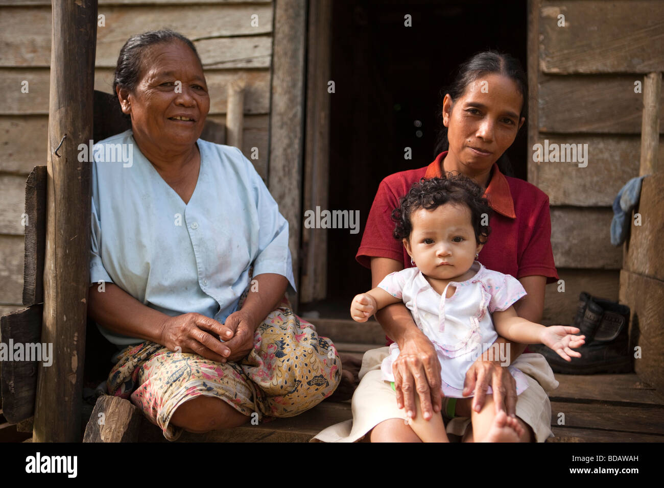 Indonesia Sulawesi Buton Labundo Bundo three generations sitting on step of house Stock Photo