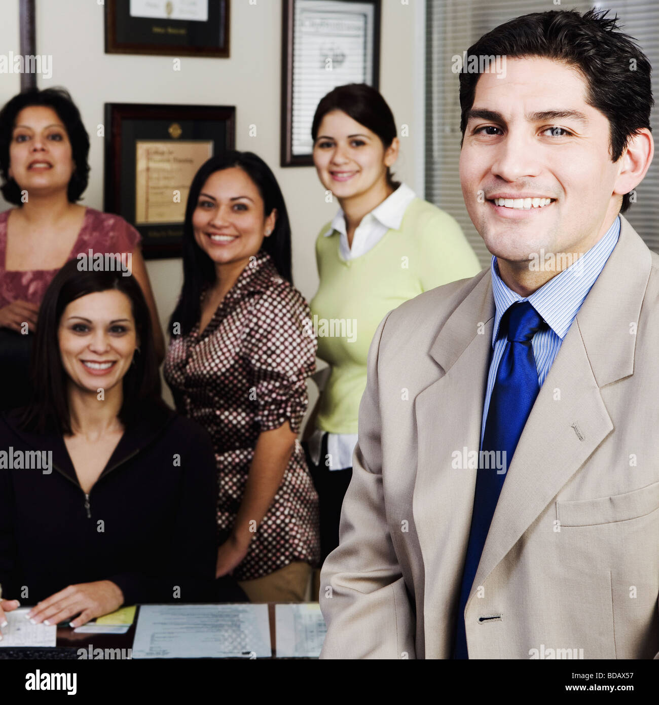 Portrait of a businessman smiling with four businesswomen in the background Stock Photo