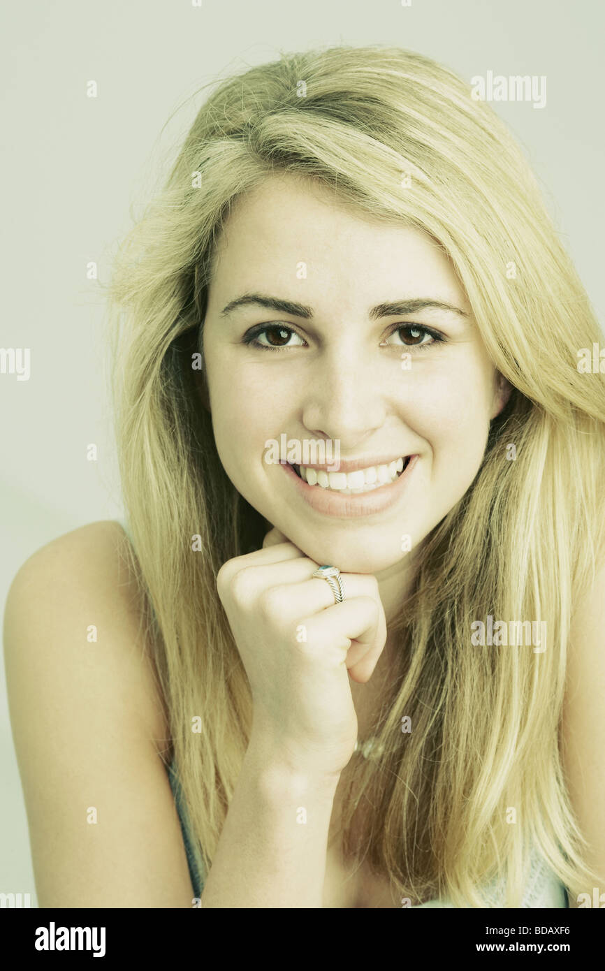Portrait of a young woman smiling with her hand on her chin Stock Photo ...