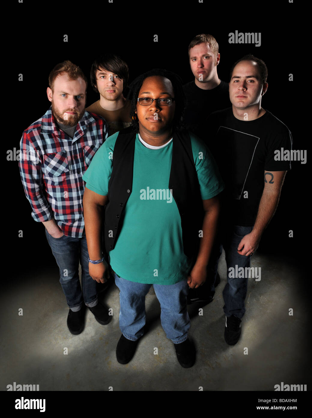 Five young men dressed in casual clothing standing over a dark background Stock Photo