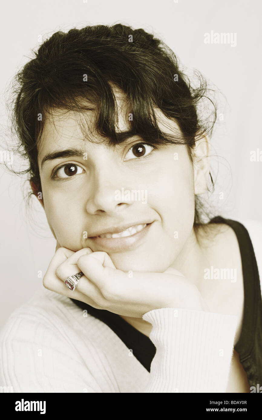 Portrait of a young woman smiling with her hand on her chin Stock Photo ...