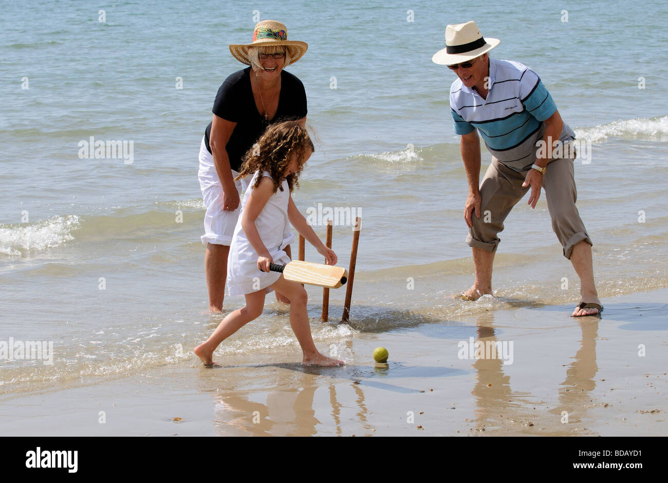 Grandparents and grandchild playing cricket at the seaside Little girl