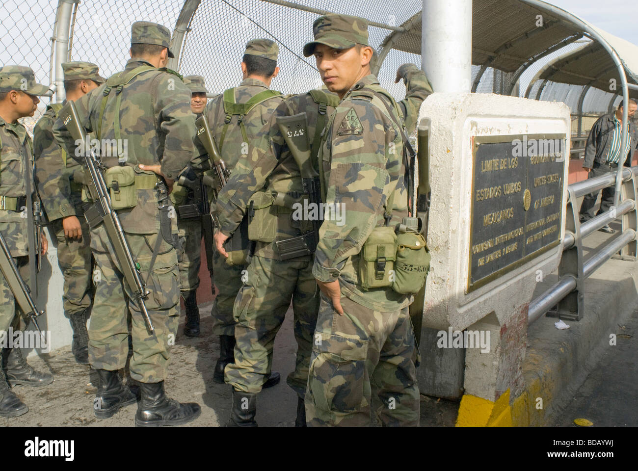 A small group of Mexican army soldiers walks along the Santa Fe Bridge between Ciudad Juarez and El Paso Texas Stock Photo