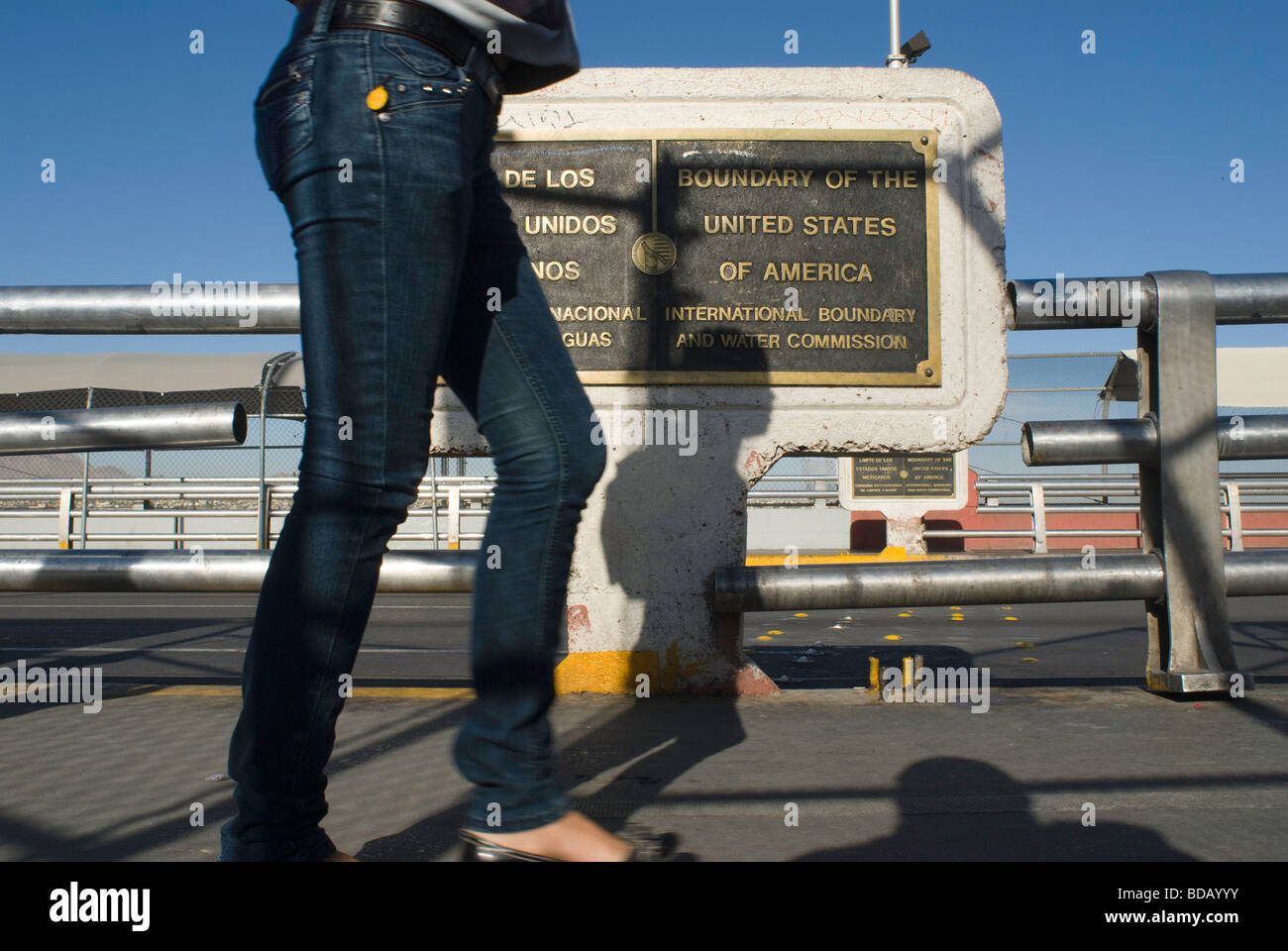 A woman walks on the Santa Fe bridge by the plaques marking the exact border between the United States and Mexico. Stock Photo