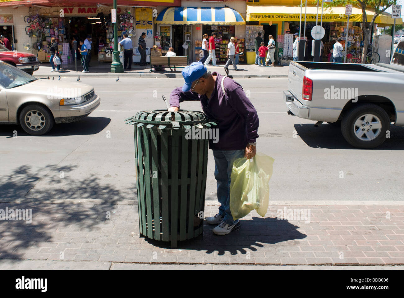 A man rummages through a public garbage container in downtown El Paso