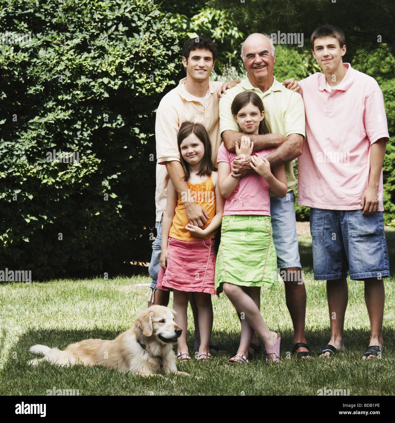 Senior man standing with his grandchildren and a dog in a park Stock Photo