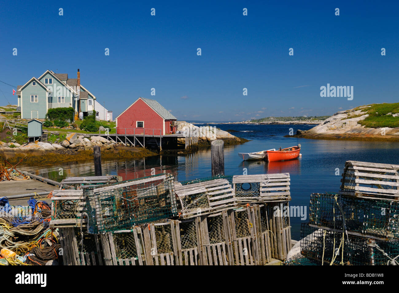 Lobster traps and rope on the wharf in the quiet fishing village of Peggy's Cove Nova Scotia Canada with blue sky on the Atlantic Ocean Stock Photo
