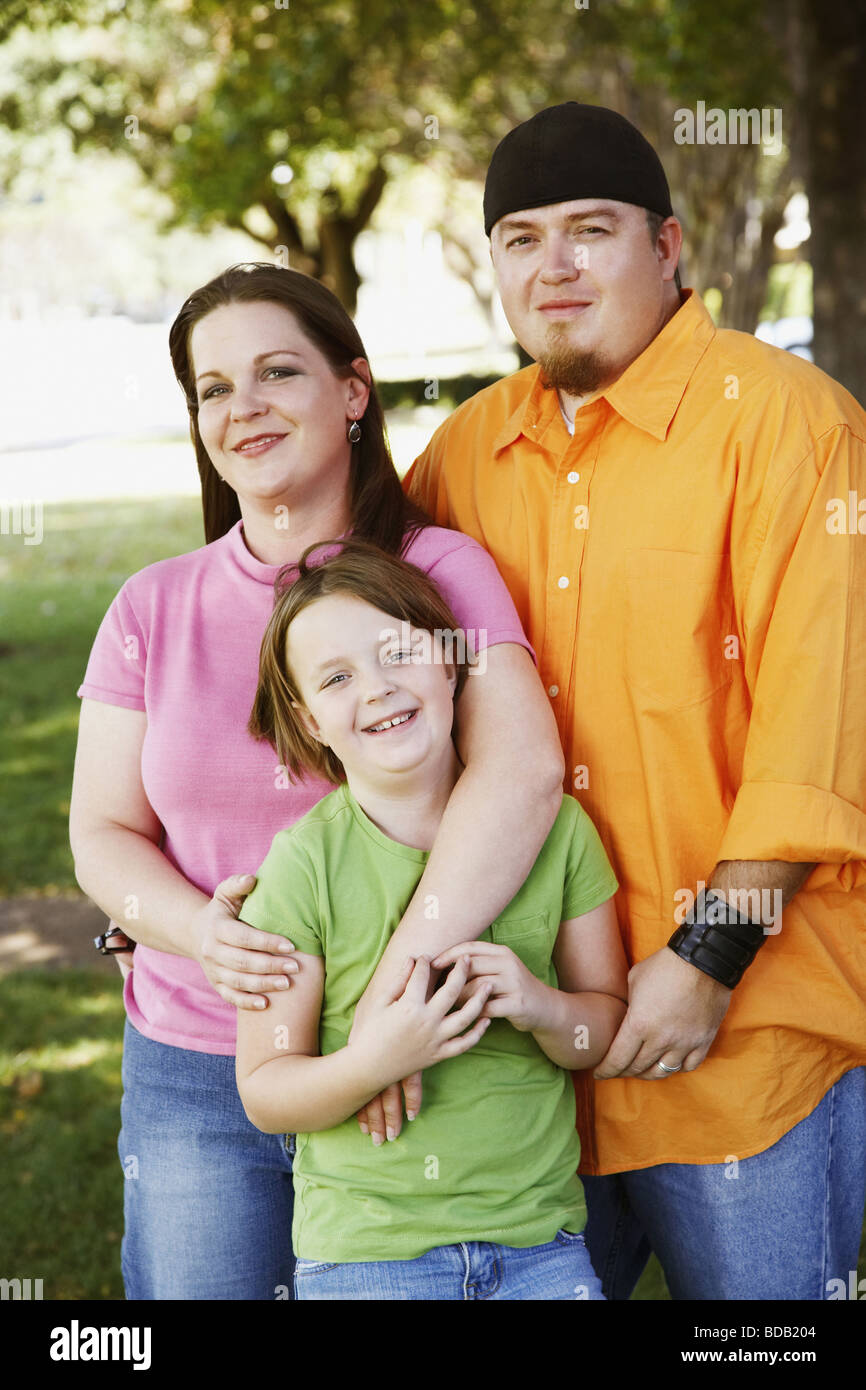 Portrait of a mid adult couple with their daughter standing in a park and smiling Stock Photo