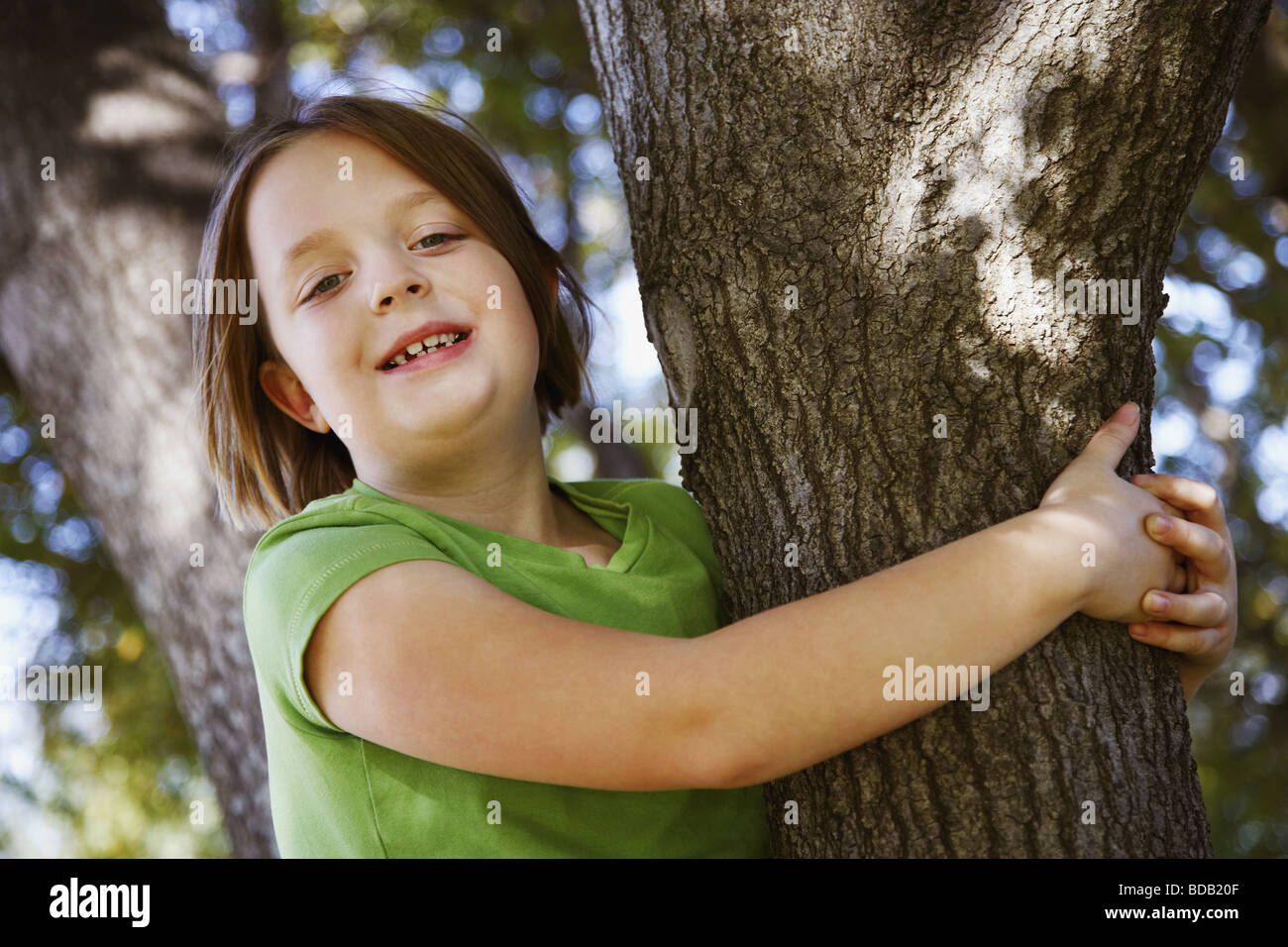 Portrait of a girl hugging a tree trunk and smiling Stock Photo