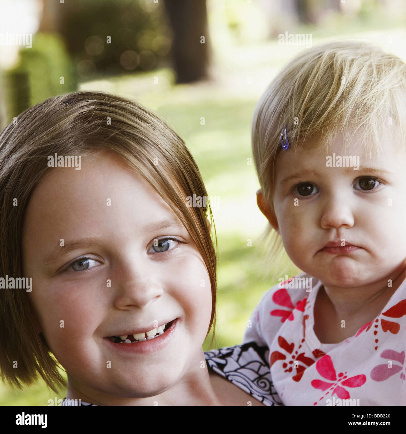 Portrait of a girl carrying her sister and smiling Stock Photo