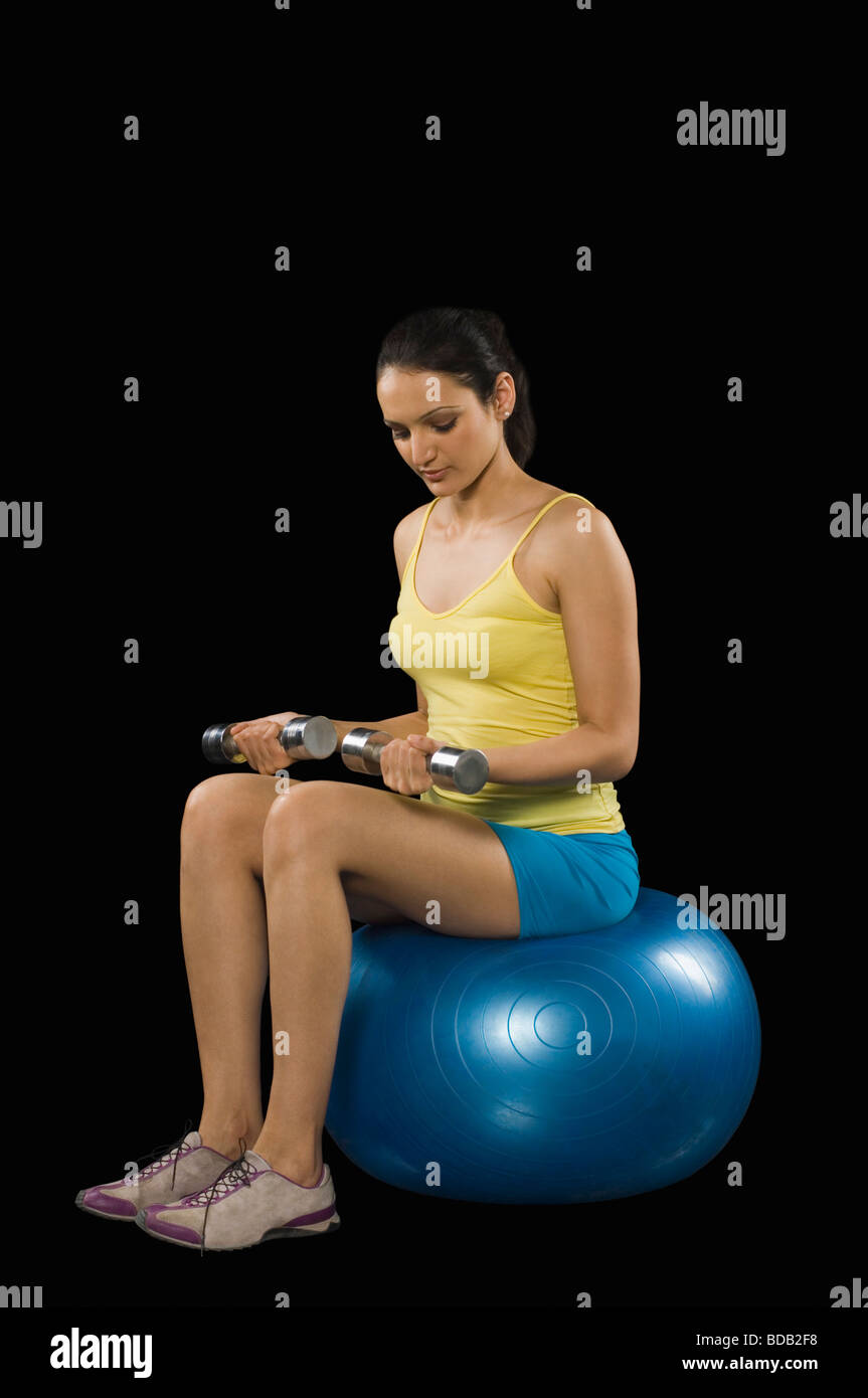 Woman exercising with dumbbells on a fitness ball Stock Photo
